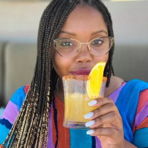 Raquel Seymone holding a gold colored cocktail